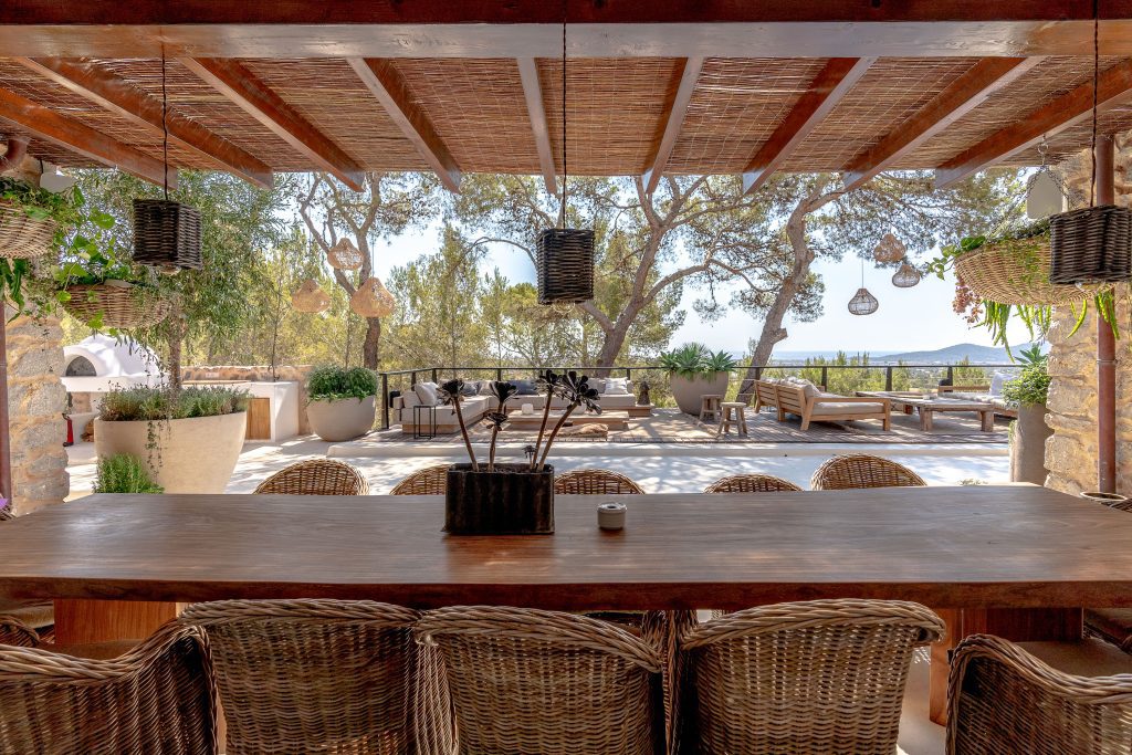 wooden table with rattan chairs facing an exterior chillout area