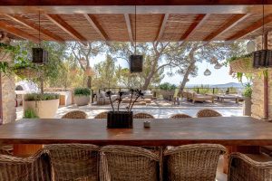 wooden table with rattan chairs facing an exterior chillout area
